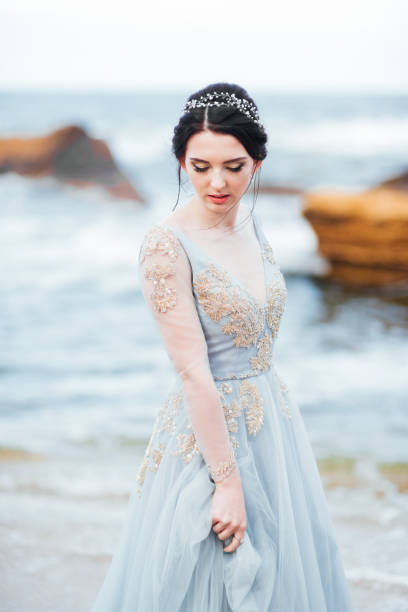 istock bride in a blue light dress walking along the ocean 1255890235