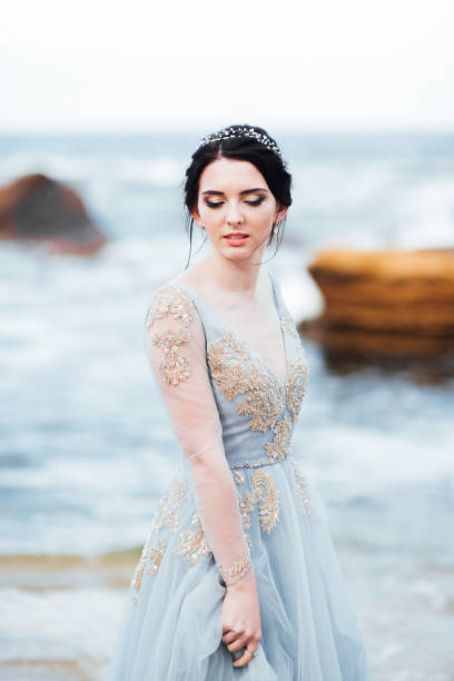 istock bride in a blue light dress walking along the ocean 1255890472