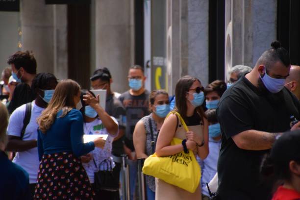 Customers with face masks queuing outside a store in London London, United Kingdom - July 12 2020: customers wearing face masks queuing outside a shop in Central London covent garden photos stock pictures, royalty-free photos & images
