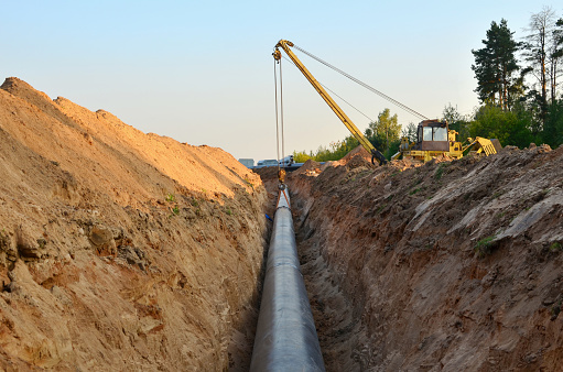 Natural gas pipeline construction work. A dug trench in the ground for the installation and installation of industrial gas and oil pipes. Crawler crane bulldozer with side boom or pipelayer