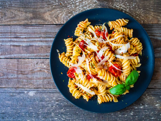 istock Penne with parmesan and tomato on wooden table 1255891408
