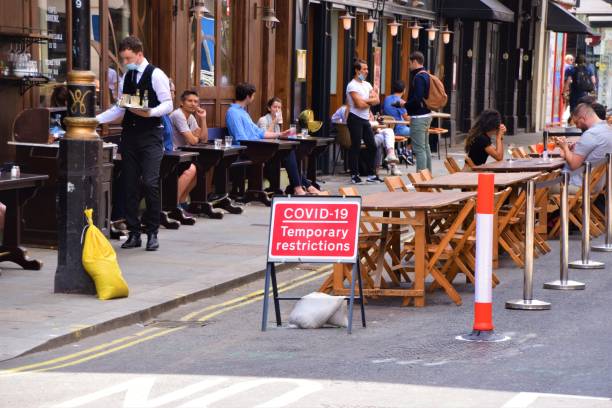 Social distancing outdoor seating with Covid-19 signs, Old Compton Street, Soho, London London, United Kingdom - July 12 2020: Social distancing cafe and restaurant temporary street seating in Old Compton Street, Soho covent garden photos stock pictures, royalty-free photos & images