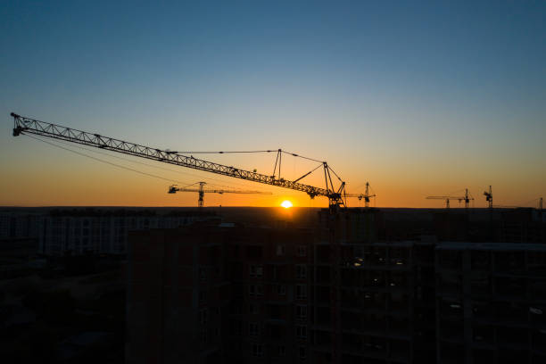 istock Aerial Drone view of silhouetteConstruction Cranes in Sunset Light. Construction Site Building in City. 1255894235