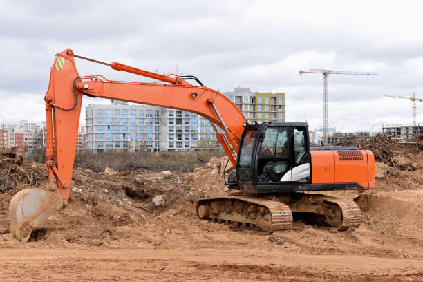 istock Red excavator during earthmoving at construction site. Backhoe dig ground for the construction of foundation and laying sewer pipes district heating. 1255901841