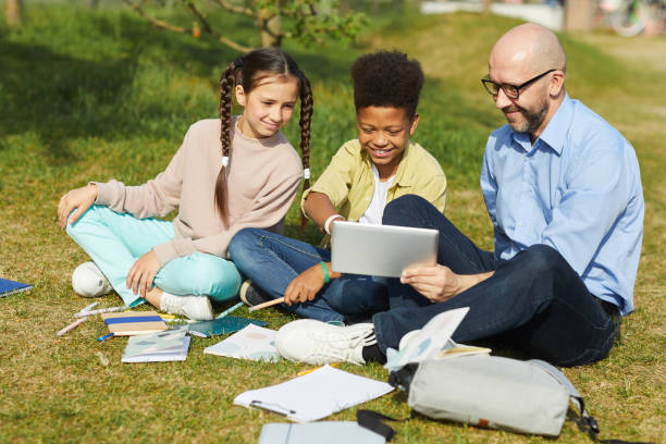 istock Two Kids with Teacher Outdoors 1255903488