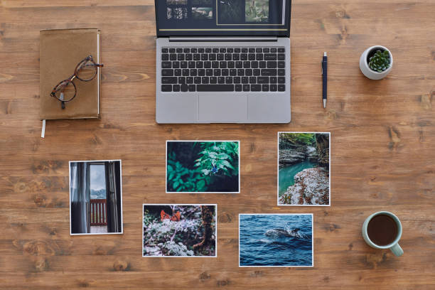 Travel Photographers Desk Top View Minimal background composition of printed photographs and laptop on textured wooden desk, photographers office, copy space graphic print photos stock pictures, royalty-free photos & images