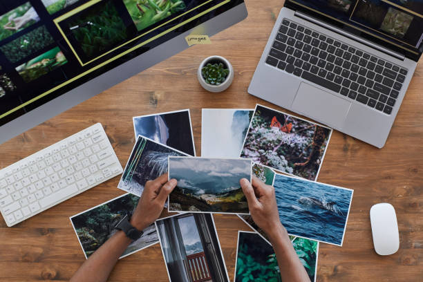 Travel Photographer Holding Pictures Top View Minimal background composition of male hands holding printed photographs over textured wooden desk, photographers office concept, copy space printing out stock pictures, royalty-free photos & images