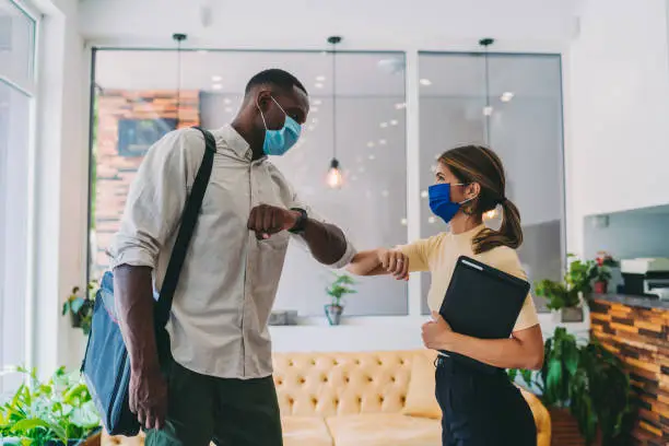 Photo of Business people greeting during COVID-19 pandemic, elbow bump