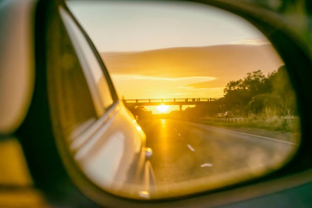 車のサイドミラーから見た日没時の道路 - バックミラー ストックフォトと画像