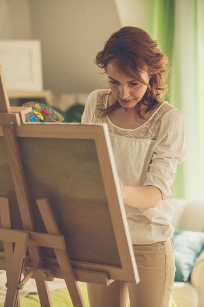 istock Woman focusing not to make a mistake while painting on easel 1255910383