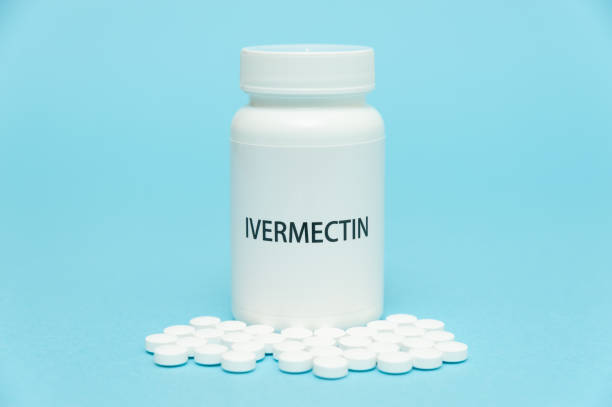 Treatments for Coronavirus (COVID-19): IVERMECTIN in white bottle packaging with scattered pills. Isolated on blue background. Horizontal shot Treatments for Coronavirus (COVID-19): IVERMECTIN in white bottle packaging with scattered pills. Isolated on blue background. Horizontal shot. food and drug administration photos stock pictures, royalty-free photos & images