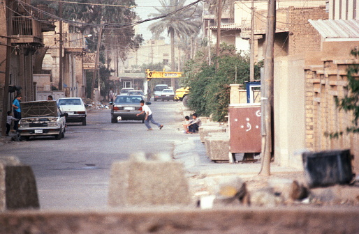 View over a roadblock of the US Army. A boy playing football.\