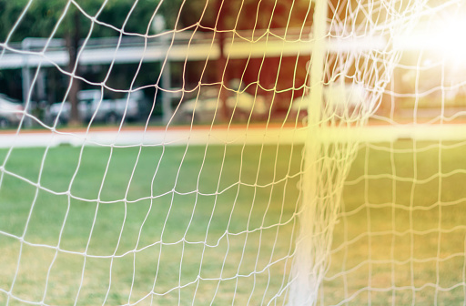 Soft focus sun flare through football net. Close up on white football net.