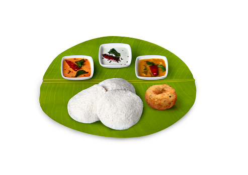 south Indian breakfast idly vada, vadai ,with coconut chutney, red chutney, and sambar served on banana leaf