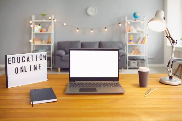 istock Online education sign and laptop computer with empty screen standing on wooden table in living room, mockup for design 1255918010