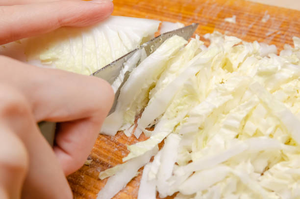 ナイフで女性の手は北京キャベツライトグリーンをカットカット。野菜サラダを調理し、サイドビュー - タケノコ白菜 ストックフォトと画像