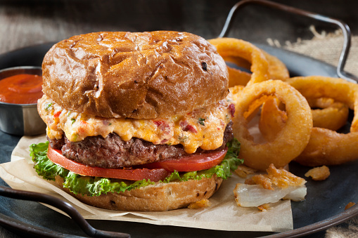 Pimento Cheese Burger with Lettuce, Tomato and Thick Cut Onion Rings on a Toasted Onion Bun