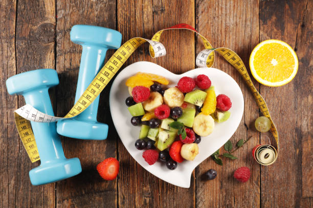 istock fresh fruit salad with dumbbell and meter tape 1255920763