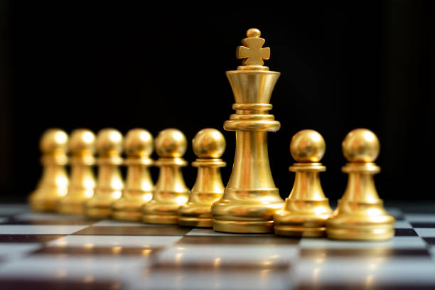 istock Gold king chess piece stand with pawn on black background (Concept of teamwork, management) 1255920807