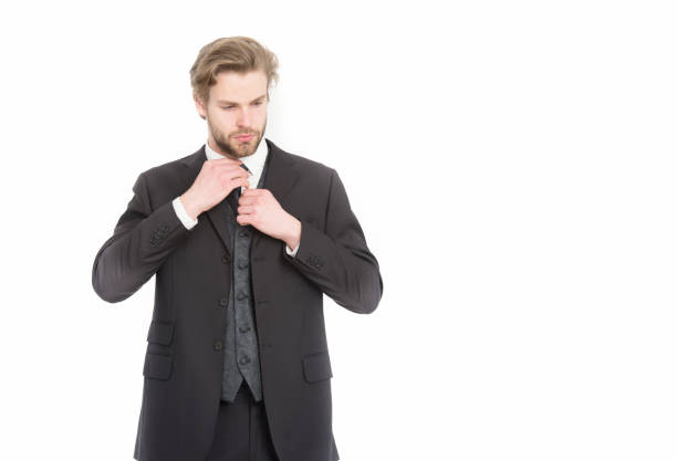 Stylish confident successful handsome young man in elegant white classic suit posing on grey isolated background, smiling and looking at camera. Studio shot of show presenter, dancer, model concept