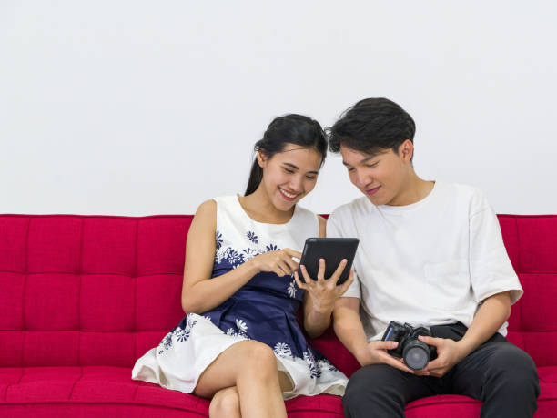istock Asian photographers allow models to view pictures taken on the tablet computer screen while sitting on a red sofa. 1255924909