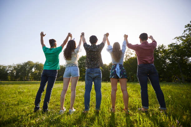 istock Raised hands of young people in a summer park 1255926467