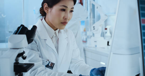 istock Genetic research laboratory interior. Asian female doctor using microscope 1255930319