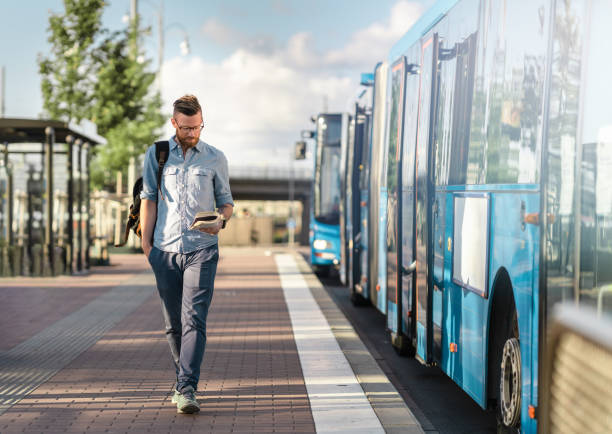 Man walking and reading a book at the bus stop