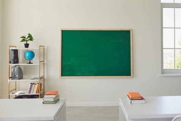 istock White school classroom interior. Bright lassroom with windows tables chair green board 1255931738