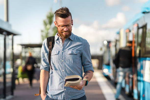 istock Man reading a book at the bus stop 1255931755