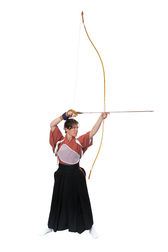 a woman practicing Kyudo is about to shoot an arrow with her bow