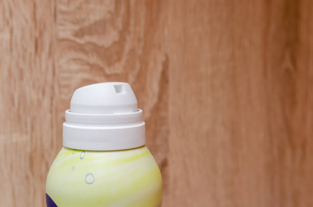 Light green bottle with white spray on wooden background close up