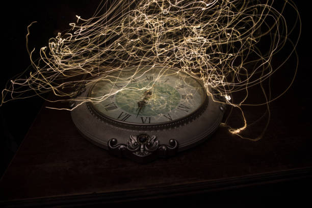 istock Time concept. Big vintage round clock on wooden table with abstract light. 1255934043