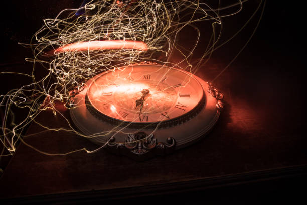 istock Time concept. Big vintage round clock on wooden table with abstract light. 1255934052