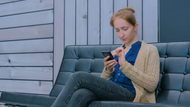 istock Young woman using smartphone on couch in modern office 1255934391