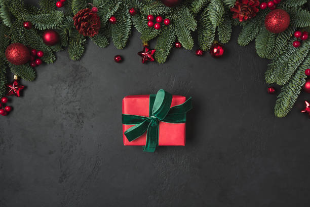 istock Christmas frame with red gift and decor, fir branches on black background. Xmas greeting card. Happy New Year. Space for text. View from above, flat lay. 1255935277