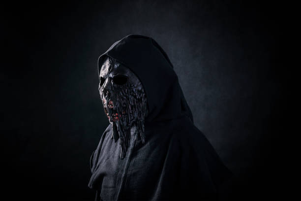 istock Scary figure in hooded cloak with mask 1255936190