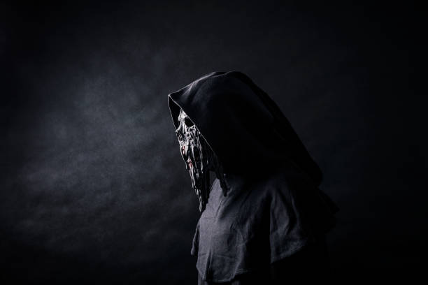 istock Scary figure in hooded cloak with mask 1255936250