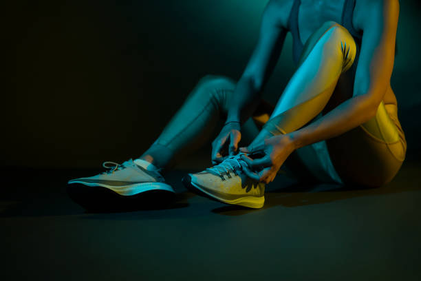 Studio shot of an unrecognizable sportswoman tying shoelaces, getting ready for the training.