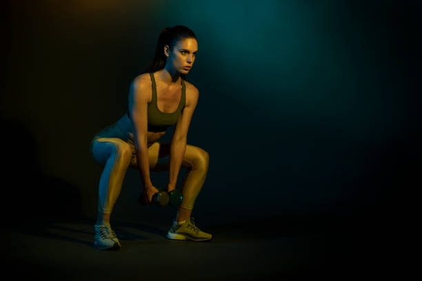 istock Studio shot of a young woman doing squats with dumbbells 1255941343