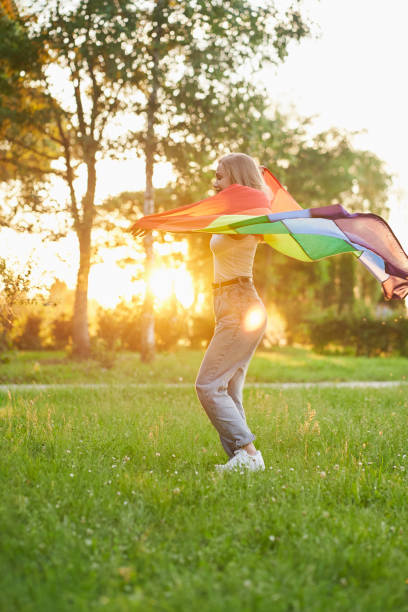 istock Laughing woman dancing with lgbt flag behind back. 1255941921
