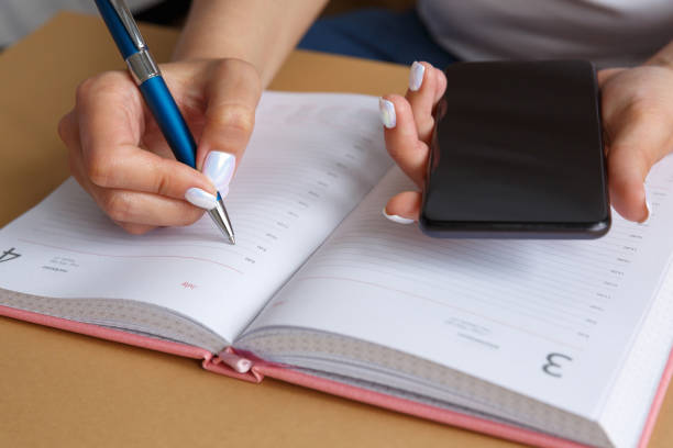 istock Man writing in a diary and holding a phone in his hand 1255945043