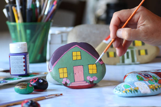 istock hand painting stone as home with small brush 1255949630