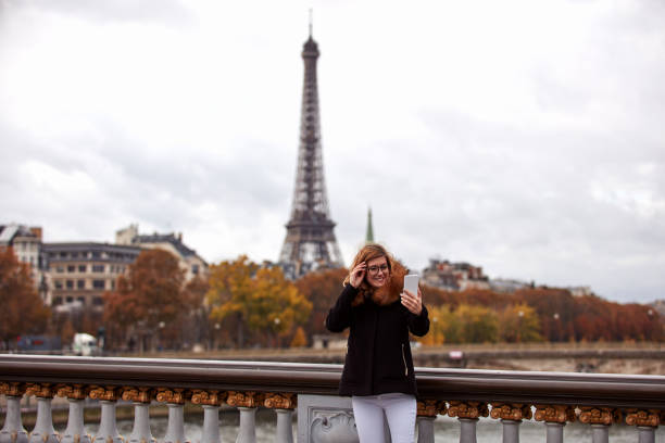 istock Girl using cellphone with Paris city background, Seine river and Eiffel tower. 1255950213