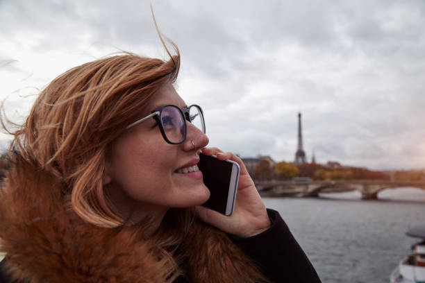 istock Girl using cellphone with Paris city background, Seine river and Eiffel tower. 1255950235