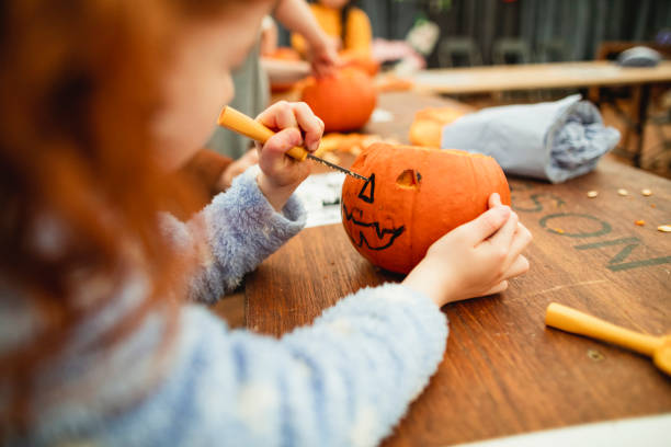 Family Carving Pumpkins Family with children carving pumpkins at a farm after picking them at a farm in preparation for Halloween. happy halloween pumpkin stock pictures, royalty-free photos & images