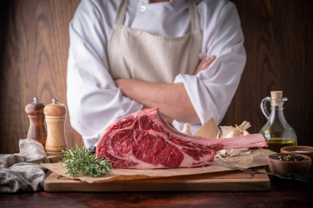 istock butcher serving fresh tomahawk steak meat to customer 1255954239