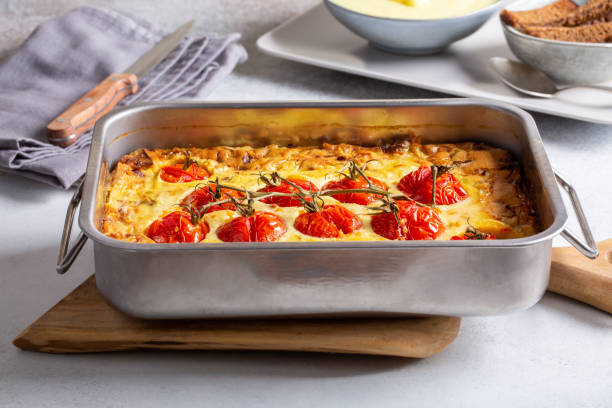 vegetable clafoutis in baking dish on concrete background, savory pie with cabbage and whole cherry tomatoes .  vegetarian cuisine. - baked breakfast cabbage cake imagens e fotografias de stock