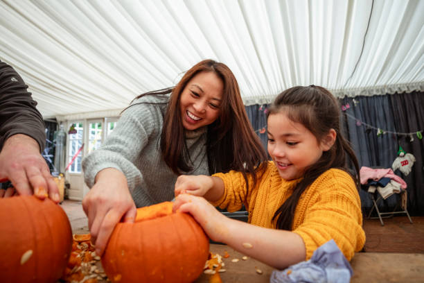 Mother and daughter carving pumpkins at a farm after picking them in preparation for Halloween.