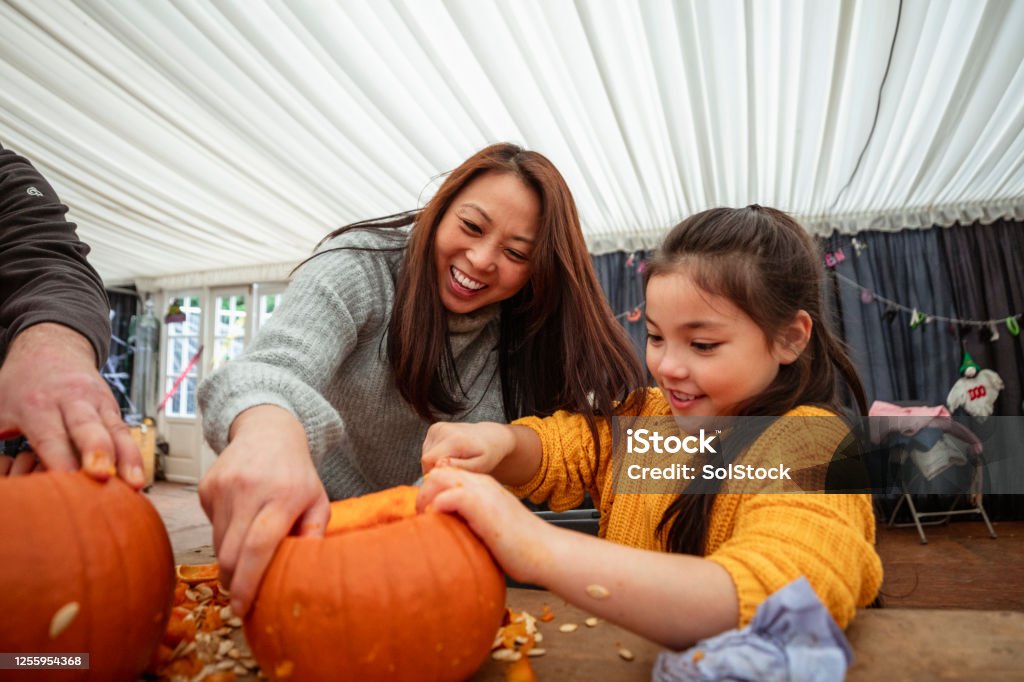 Mother and Daughter Carving Pumpkins Mother and daughter carving pumpkins at a farm after picking them in preparation for Halloween. Pumpkin Stock Photo